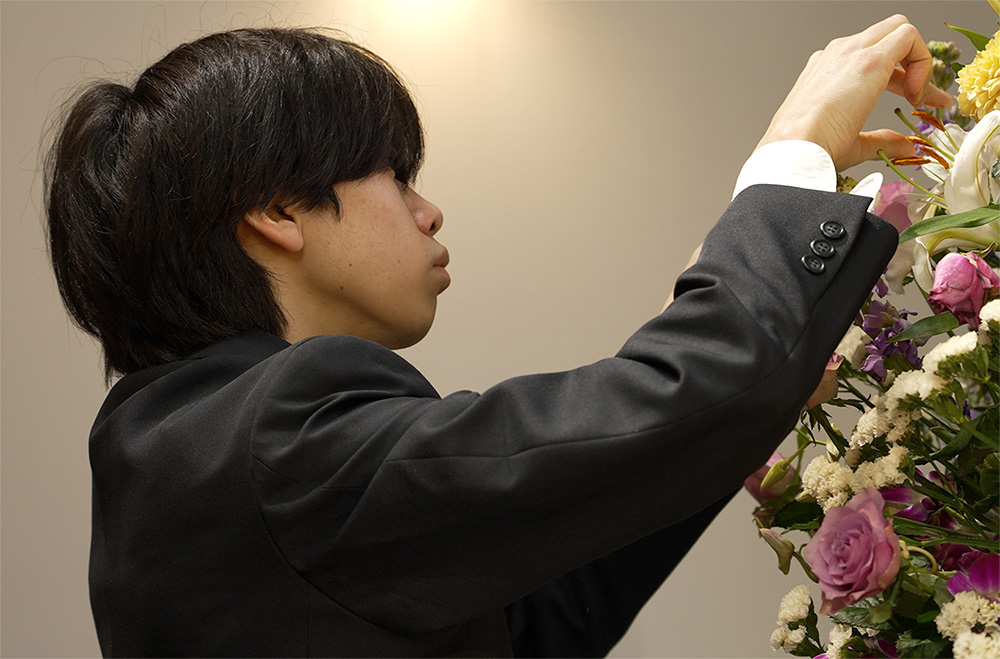 [写真]花束を整えている男性