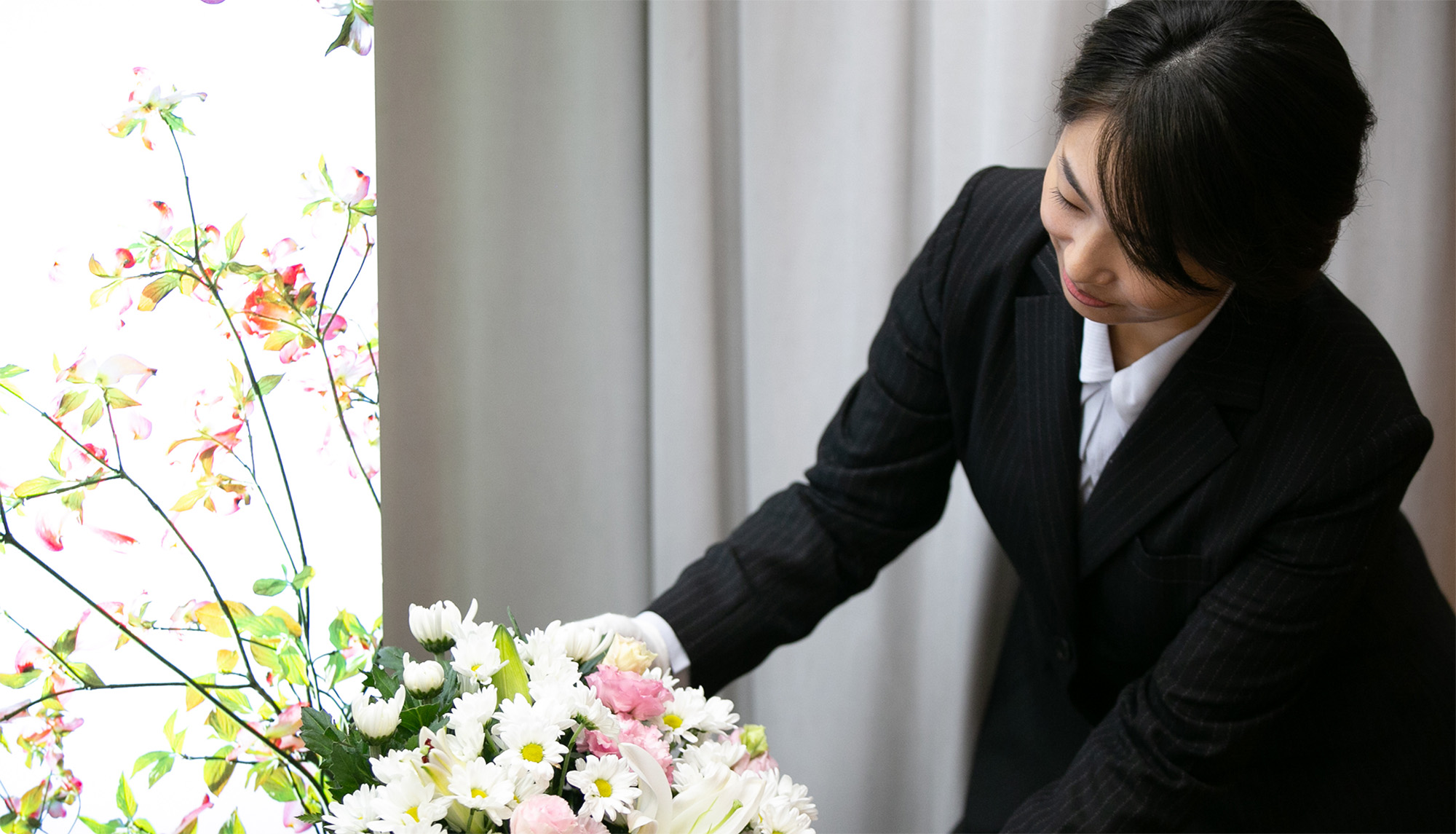 [写真]祭壇や会場に飾る供花を心を込めて整える女性スタッフの様子
