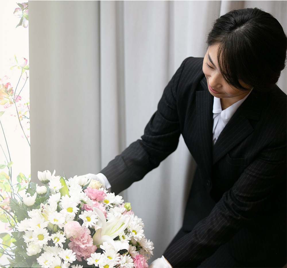 [写真]祭壇や会場に飾る供花を心を込めて整える女性スタッフの様子